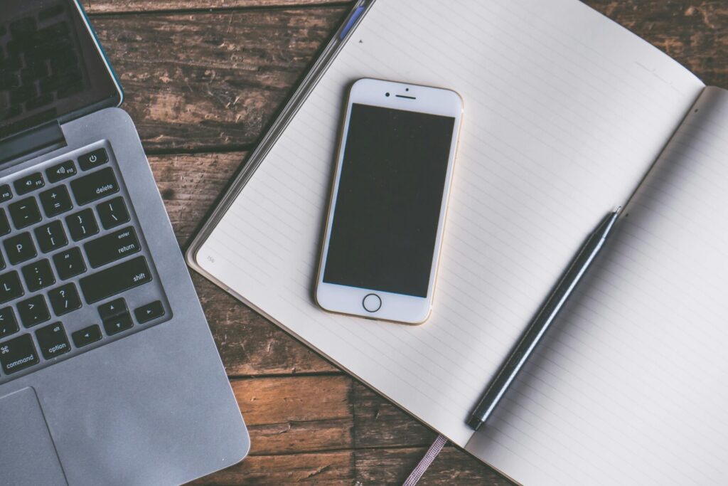Image d'un bloc note avec un stylo, un téléphone portable, Android ou Smartphone étteint, un Laptop.