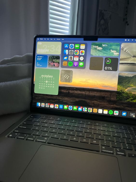 Image, photo d'une photographie rapprochée d'un ordinateur portable sur un lit, avec un écran affichant plusieurs fenêtres et icônes d'applications.