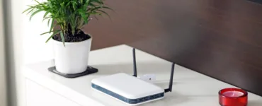 Optimiser votre wifi : image, photo d'une box internet placée sur une table avec un cendrier et un pot de fleurs.