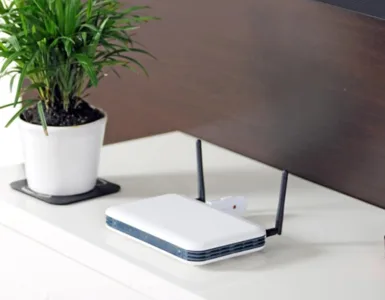 Optimiser votre wifi : image, photo d'une box internet placée sur une table avec un cendrier et un pot de fleurs.