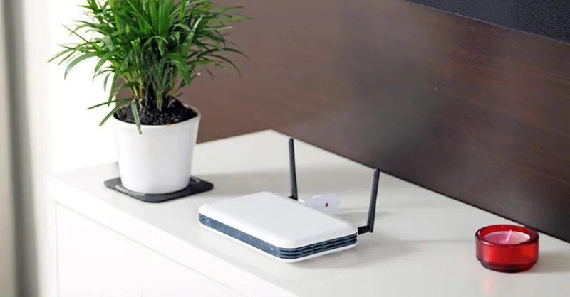 Optimiser votre wifi : image, photo d'une box internet placée sur une table avec un cendrier et un pot de fleurs.