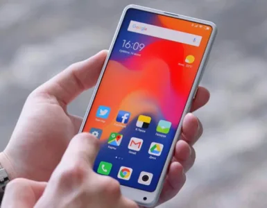 Optimiser son smartphone : image, photo d'une main qui tient un téléphone affichant un écran clair avec le mot “Settings” ou “Réglages” visible.