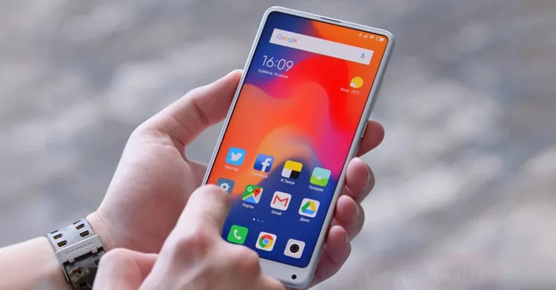 Optimiser son smartphone : image, photo d'une main qui tient un téléphone affichant un écran clair avec le mot “Settings” ou “Réglages” visible.