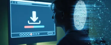 Télécharger sans laisser de traces : image ou photo d'un personnage assis devant un ordinateur éclairé uniquement par l’écran. Sur l’écran, on voit une icône de téléchargement avec une barre de progression.