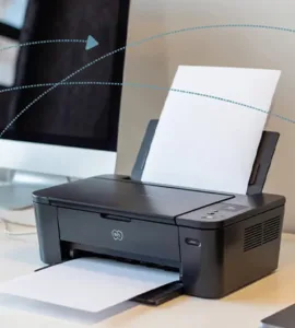 Partage d'une imprimante : image ou photo d'un bureau moderne avec deux ordinateurs portables et un ordinateur de bureau connectés à une même imprimante Wi-Fi au centre. Des lignes de connexion discrètes illustrent le réseau local entre les appareils et l'imprimante.