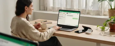 WhatsApp : image ou photo d'un utilisateur assis devant un ordinateur portable affichant l’interface de WhatsApp, avec un smartphone posé à côté mais éteint.