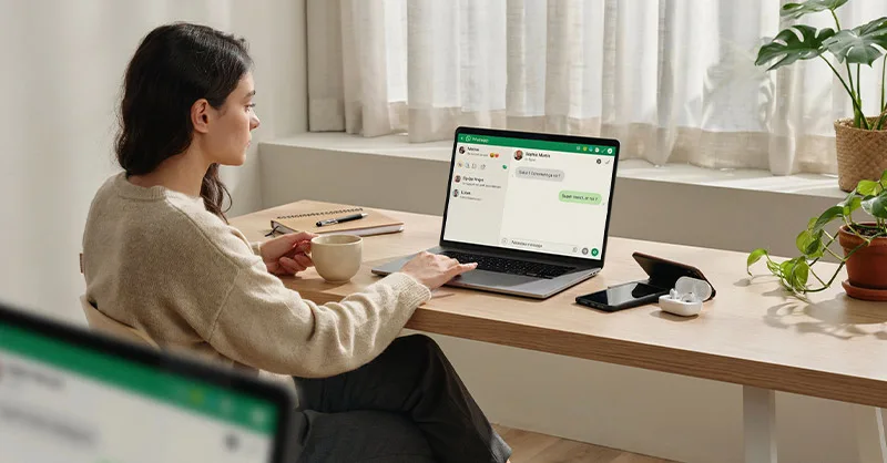 WhatsApp : image ou photo d'un utilisateur assis devant un ordinateur portable affichant l’interface de WhatsApp, avec un smartphone posé à côté mais éteint.